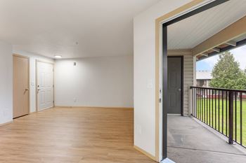 A room with wooden floors and white walls, with a black railing on the balcony.